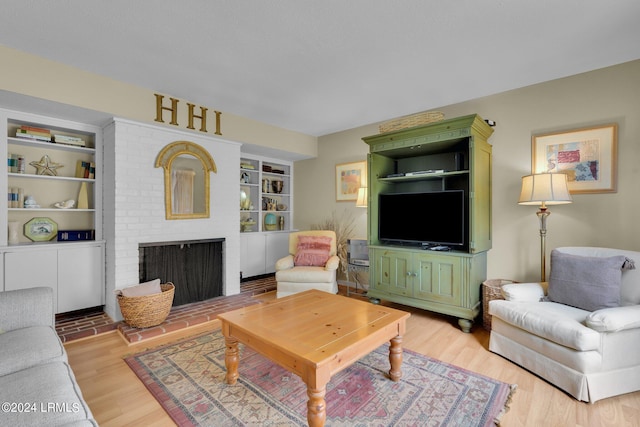 living room featuring a brick fireplace, built in shelves, and light hardwood / wood-style floors