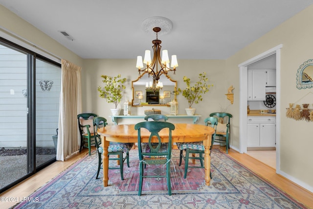 dining room with a healthy amount of sunlight, light hardwood / wood-style flooring, and a chandelier