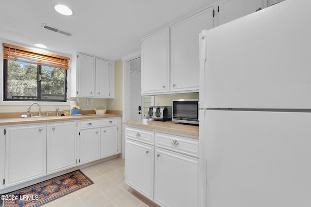 kitchen with white cabinetry, sink, and white refrigerator