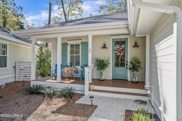 entrance to property featuring a porch and a shingled roof