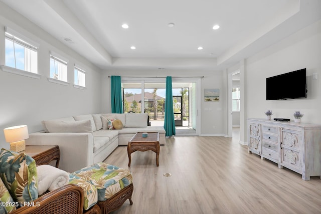 living room featuring baseboards, a tray ceiling, recessed lighting, and light wood-style floors
