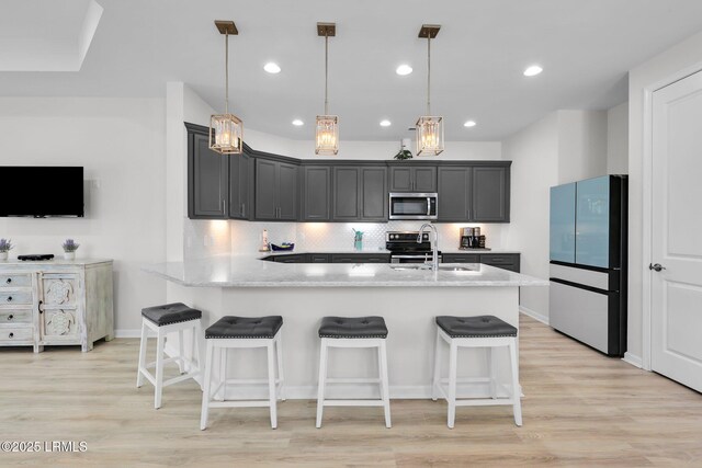 kitchen featuring backsplash, a sink, light stone countertops, a peninsula, and stainless steel appliances