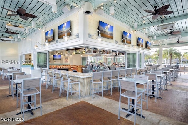 dining space with track lighting, a high ceiling, a community bar, tile patterned flooring, and ceiling fan