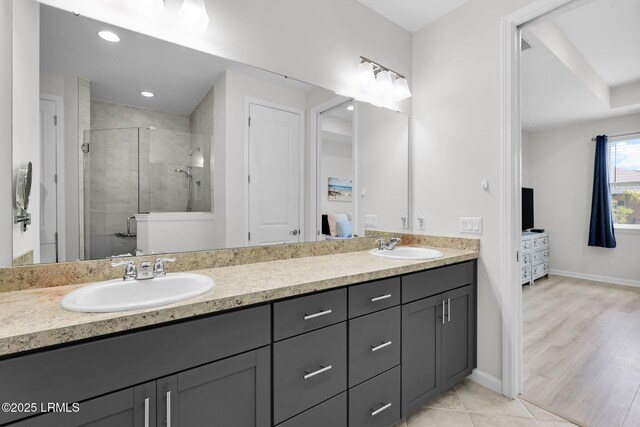 bathroom featuring double vanity, a sink, baseboards, and a shower stall
