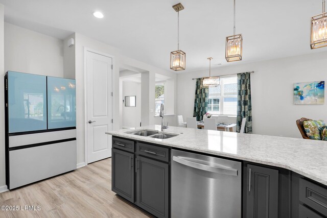kitchen featuring light wood finished floors, dishwasher, light stone countertops, a sink, and hanging light fixtures