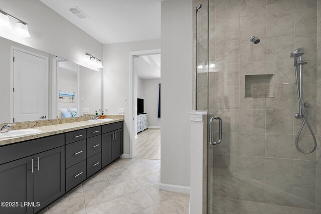 ensuite bathroom featuring connected bathroom, a sink, a shower stall, visible vents, and double vanity