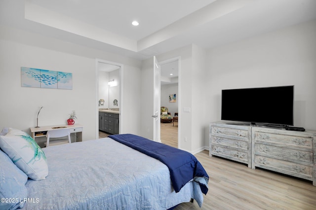 bedroom featuring ensuite bathroom, baseboards, wood finished floors, recessed lighting, and a raised ceiling
