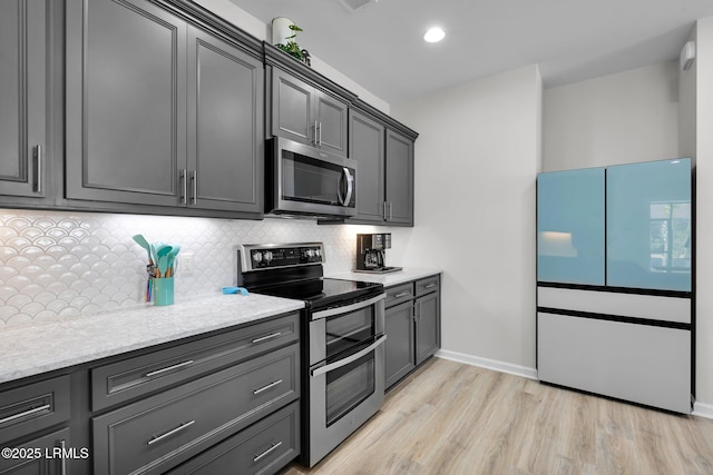 kitchen with stainless steel appliances, baseboards, decorative backsplash, light wood-style flooring, and light stone countertops