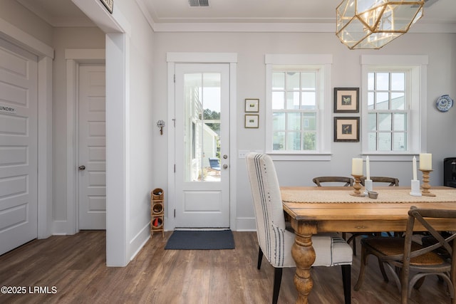 dining space featuring a notable chandelier, crown molding, visible vents, baseboards, and dark wood-style floors