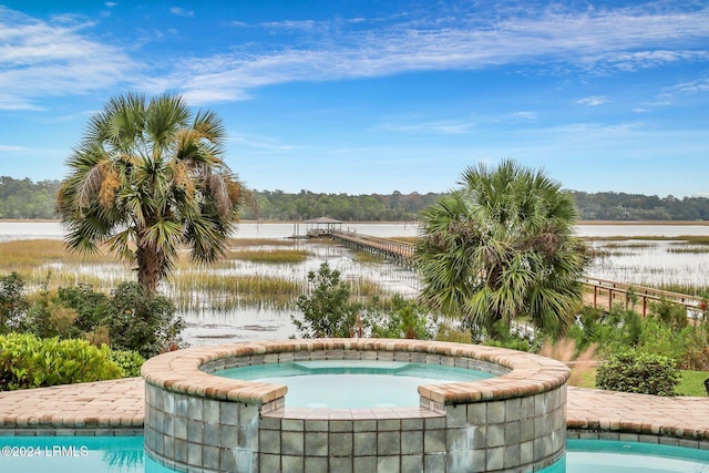 view of swimming pool with an in ground hot tub and a water view