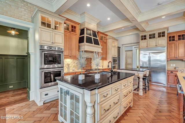 kitchen featuring a center island with sink, crown molding, light parquet floors, and built in appliances