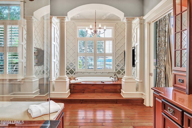 bathroom with a healthy amount of sunlight, wood-type flooring, decorative columns, and a chandelier