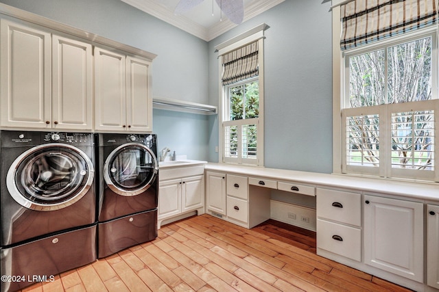 clothes washing area with separate washer and dryer, sink, cabinets, and a healthy amount of sunlight