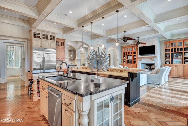 kitchen with hanging light fixtures, light parquet flooring, stainless steel built in fridge, and a center island with sink