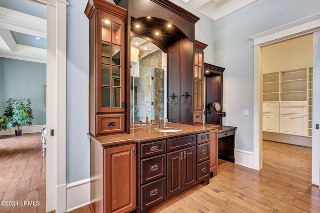 bar featuring crown molding, light hardwood / wood-style floors, and sink