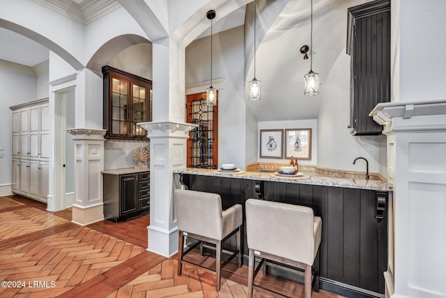 bar with sink, decorative light fixtures, parquet floors, ornamental molding, and light stone countertops