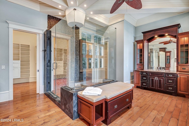 interior space with beamed ceiling, sink, ornamental molding, ceiling fan, and light wood-type flooring