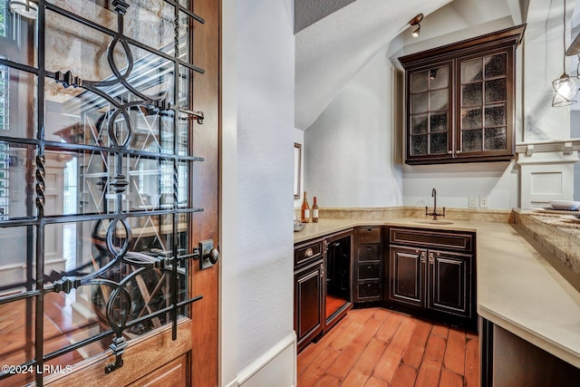 bar featuring dark brown cabinets, sink, and light hardwood / wood-style floors