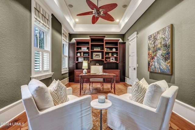 interior space featuring ceiling fan, ornamental molding, a tray ceiling, and light parquet flooring