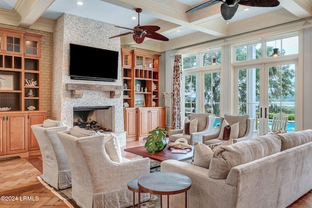 living room with light parquet flooring, a stone fireplace, coffered ceiling, and beam ceiling