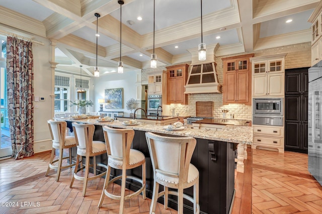 kitchen with stainless steel microwave, light parquet flooring, light stone countertops, and hanging light fixtures