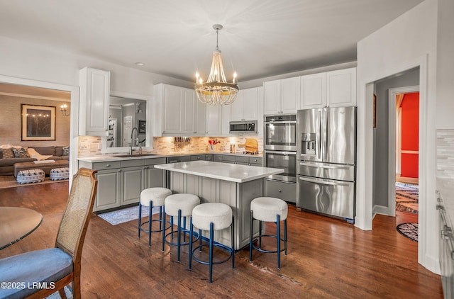 70 Dolphin Point Dr, Beaufort, SC 29907 - kitchen featuring appliances with stainless steel finishes, a chandelier, a kitchen island, tasteful backsplash, and dark wood-style flooring