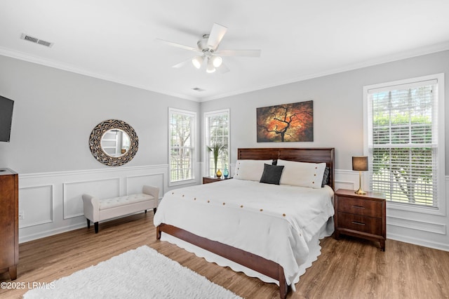 170 Pinecrest Cir, Bluffton, SC 29910 - bedroom with wood finished floors, crown molding, multiple windows, a decorative wall, and wainscoting