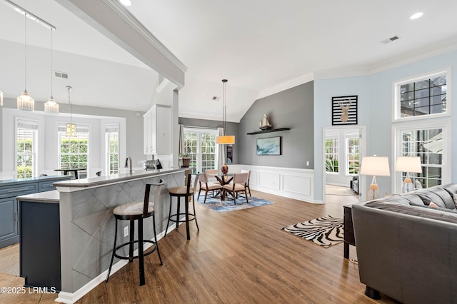 170 Pinecrest Cir, Bluffton, SC 29910 - kitchen featuring crown molding, wood finished floors, open floor plan, a kitchen breakfast bar, and wainscoting