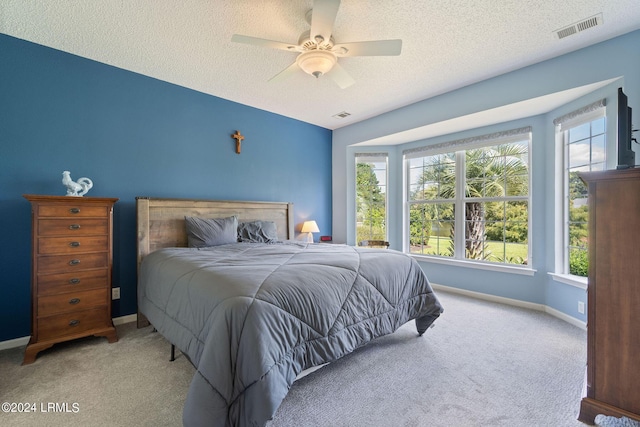 carpeted bedroom featuring multiple windows, a textured ceiling, and ceiling fan