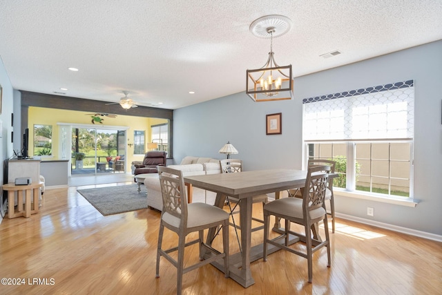 dining area with plenty of natural light, a textured ceiling, light wood-type flooring, and baseboards