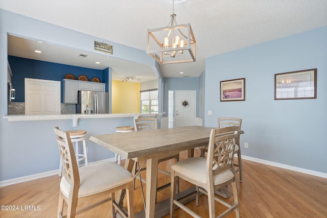 dining space featuring visible vents, baseboards, light wood-style floors, and a textured ceiling