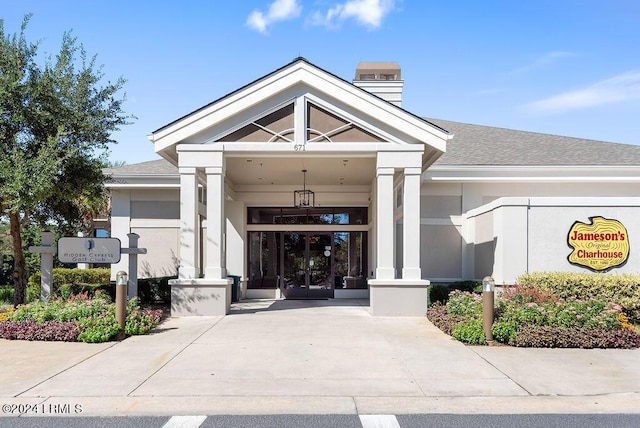 doorway to property featuring stucco siding, french doors, and a shingled roof