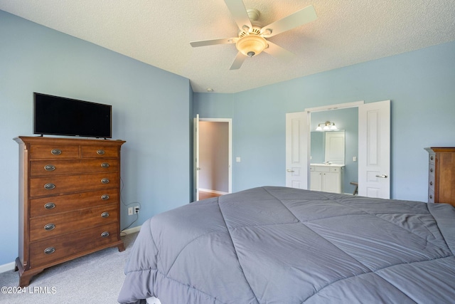 bedroom with baseboards, ceiling fan, ensuite bathroom, a textured ceiling, and light carpet