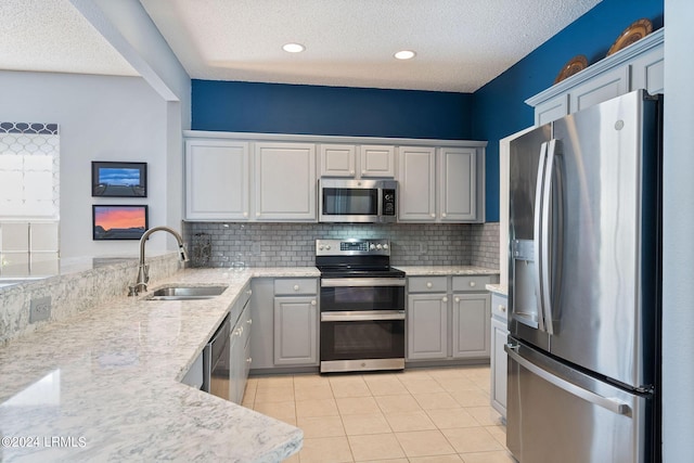 kitchen featuring appliances with stainless steel finishes, gray cabinets, sink, and a textured ceiling