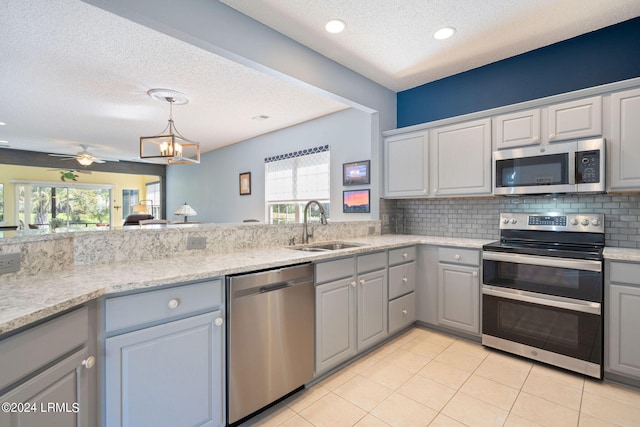 kitchen with a healthy amount of sunlight, decorative backsplash, gray cabinets, appliances with stainless steel finishes, and a sink