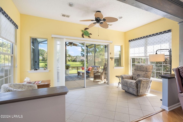 sitting room with a healthy amount of sunlight, light tile patterned floors, a textured ceiling, and ceiling fan