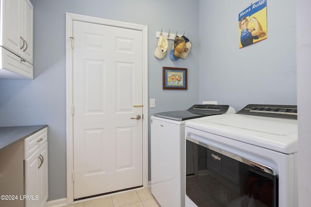 washroom featuring cabinets, light tile patterned flooring, and washer and clothes dryer