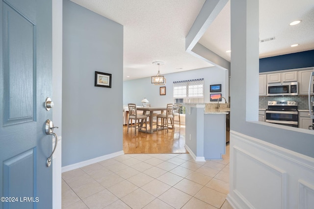 foyer with sink, a textured ceiling, and light tile patterned floors