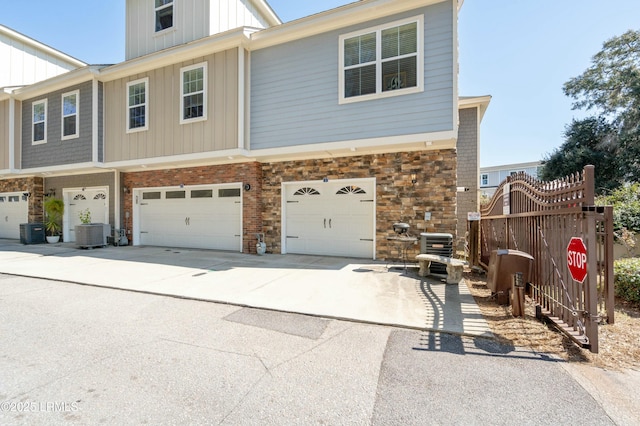 multi unit property with central air condition unit, a garage, brick siding, concrete driveway, and board and batten siding