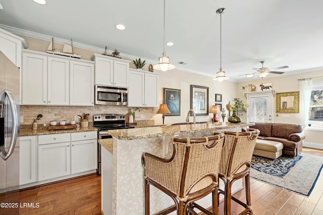 kitchen featuring appliances with stainless steel finishes, light wood-style floors, crown molding, and decorative backsplash