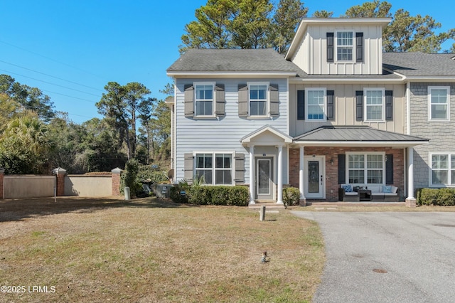 view of front of home with fence, a porch, board and batten siding, and a front yard