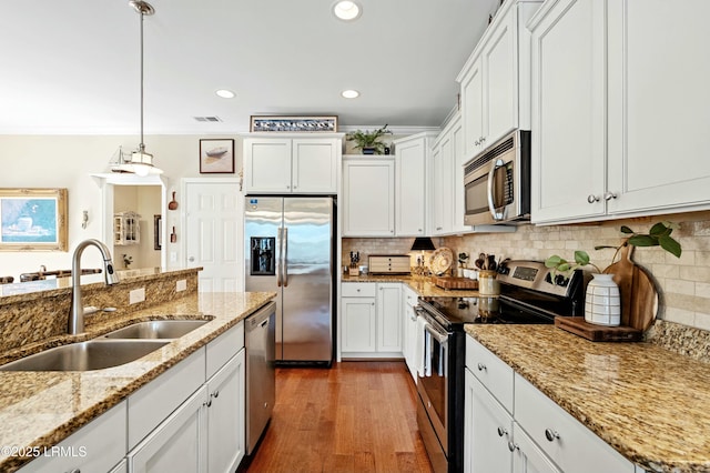 kitchen with stainless steel appliances, dark wood-type flooring, a sink, white cabinets, and tasteful backsplash