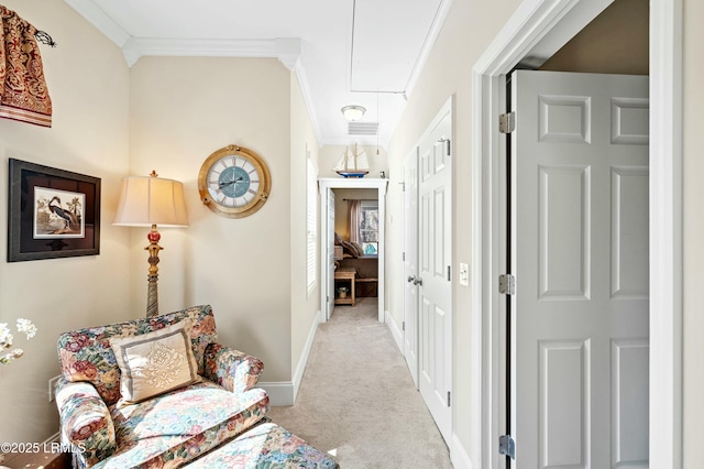 hall with attic access, visible vents, baseboards, ornamental molding, and carpet floors