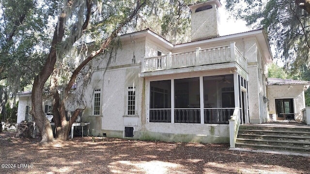 rear view of house featuring a sunroom and a balcony