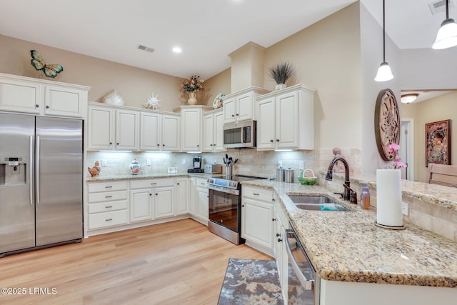 kitchen featuring sink, hanging light fixtures, white cabinets, and appliances with stainless steel finishes