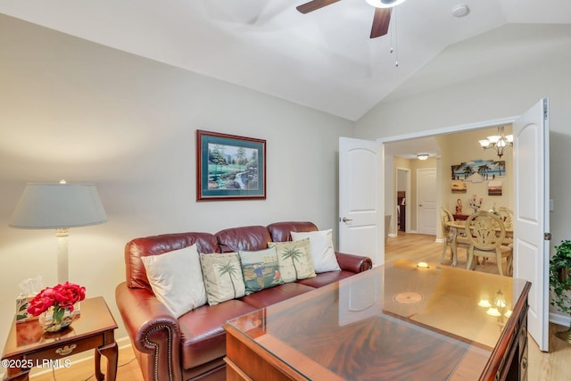 living room featuring lofted ceiling, ceiling fan with notable chandelier, and light hardwood / wood-style flooring