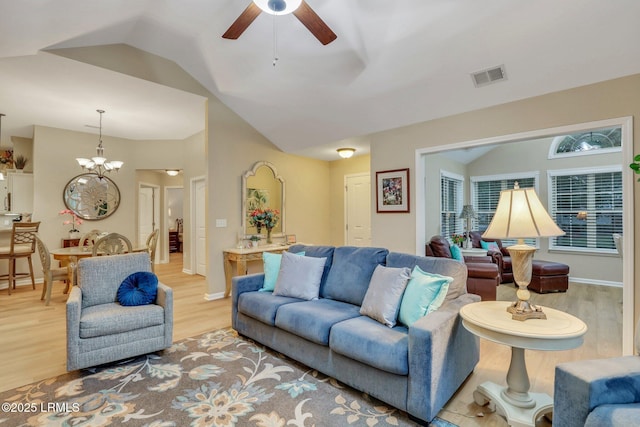 living room featuring vaulted ceiling, ceiling fan with notable chandelier, and light wood-type flooring