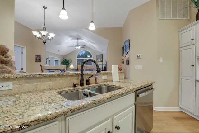 kitchen with light stone counters, stainless steel dishwasher, sink, and pendant lighting