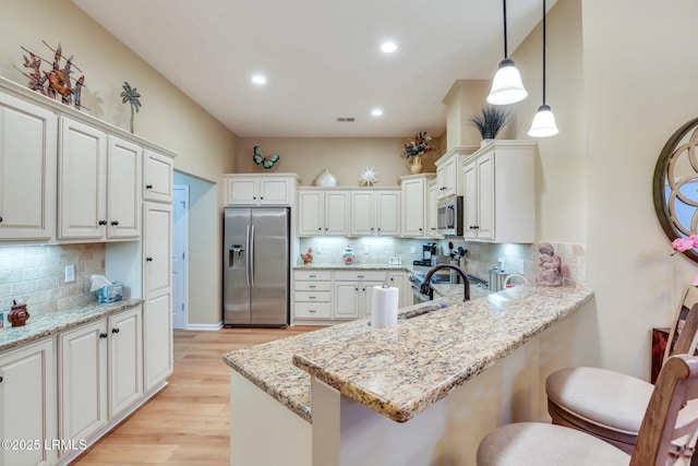 kitchen with pendant lighting, a breakfast bar, white cabinets, and appliances with stainless steel finishes