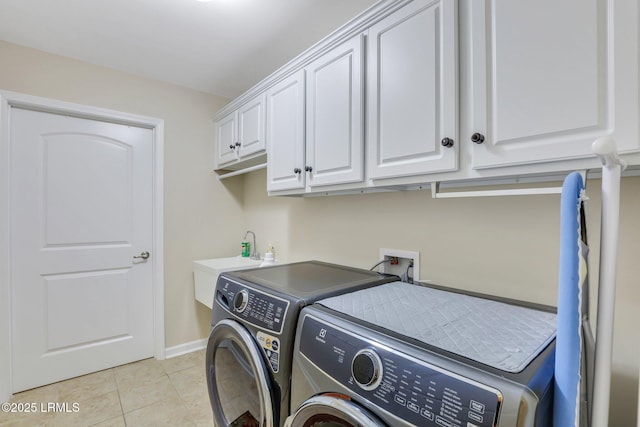 laundry room featuring sink, washer and clothes dryer, cabinets, and light tile patterned flooring